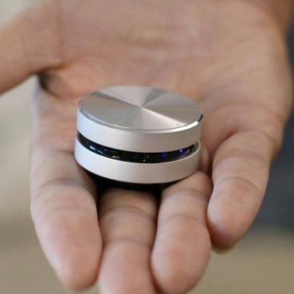 A compact metal Grommet gadget resting in an open palm