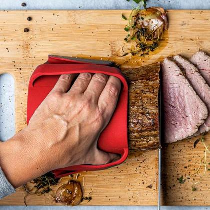A hand wiping a silicone mat covering a carving board