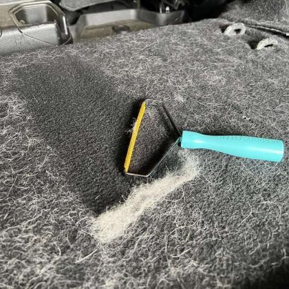 A pet hair remover lifting fur off a gray blanket